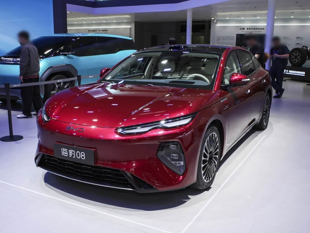 Red BYD Seal 08 2026 electric sedan at auto show, front three-quarter view, large executive EV with standard rear-wheel steering